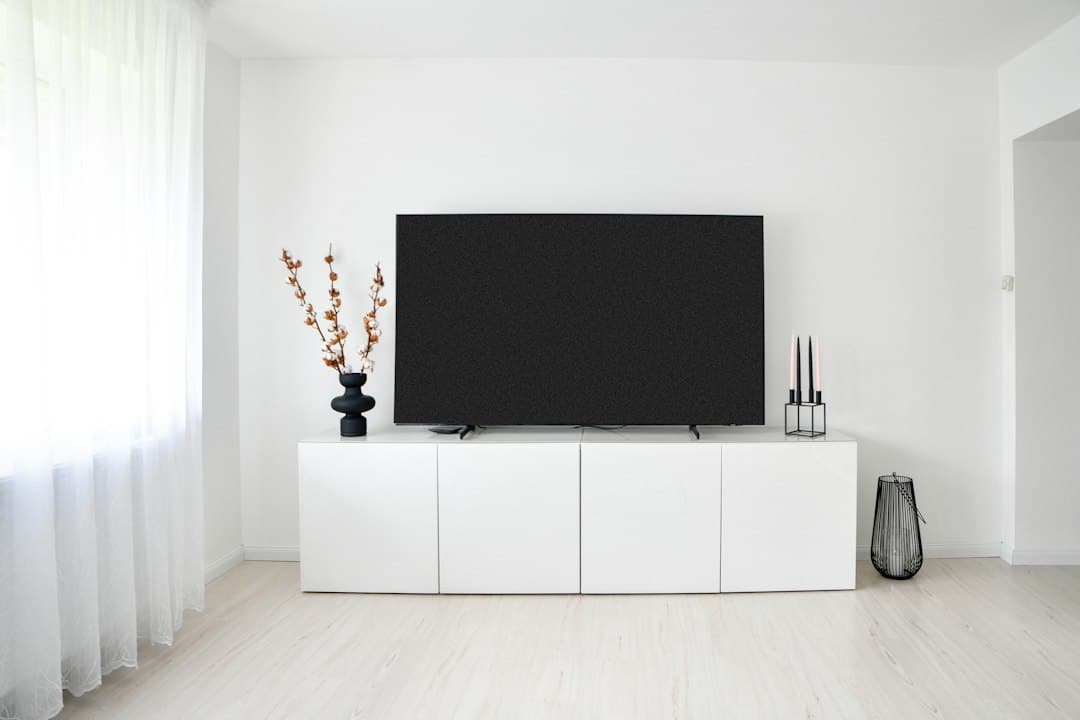 Platt-tv på vit tv-bänk i ljust vardagsrum